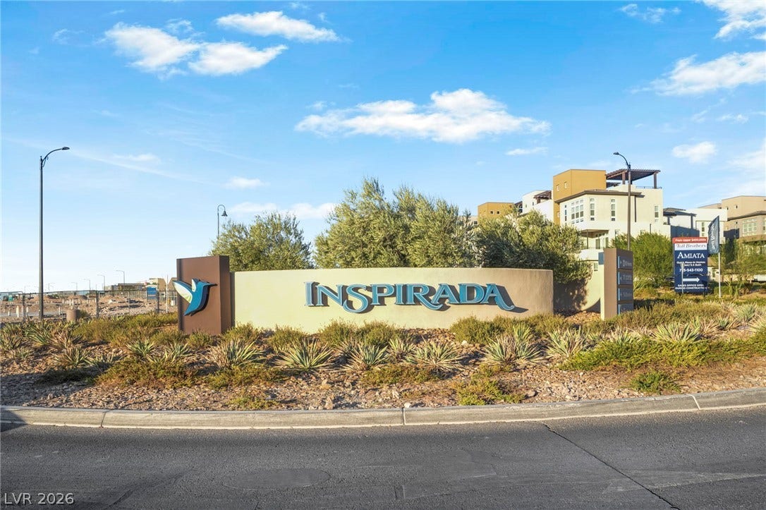 An inviting entrance to a modern community, featuring manicured desert landscaping and contemporary architectural styles.