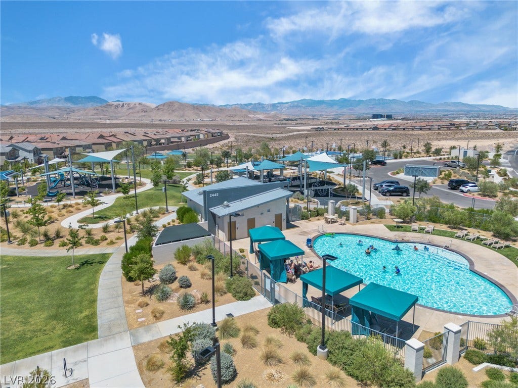 An aerial perspective reveals a vibrant community pool area set against a backdrop of distant mountains.