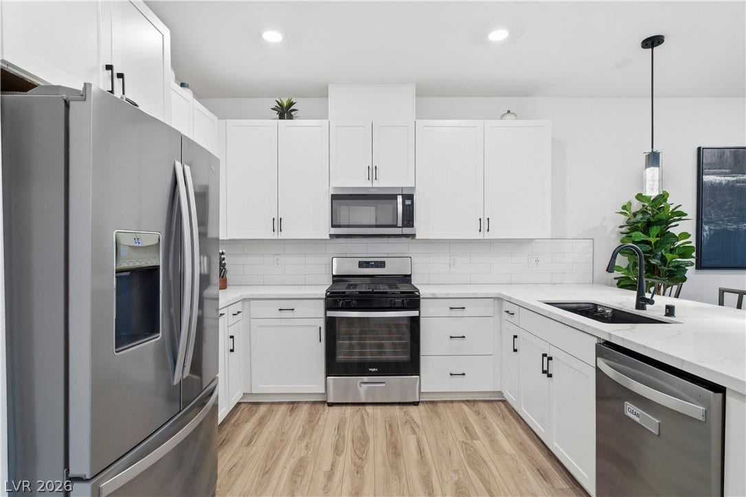 A well-appointed kitchen features stainless steel appliances, gleaming countertops, and stylish white cabinetry.