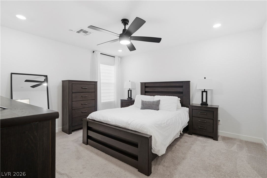 Well-lit bedroom showcasing plush carpet flooring and a ceiling fan for comfort.