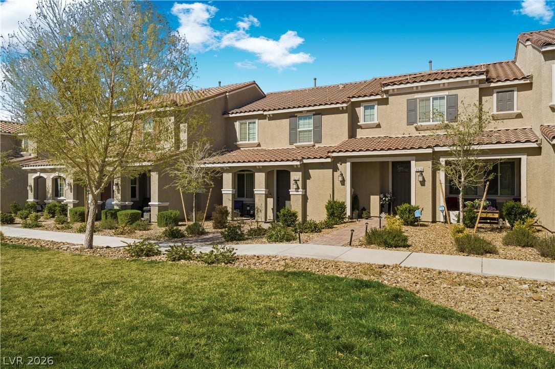 A terracotta-tiled roof crowns this residence with shutters and tidy landscaping.