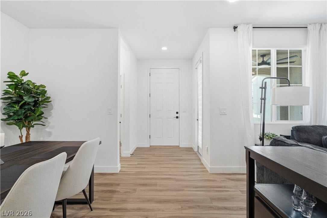 A welcoming entryway with natural wood flooring leads to a spacious living area and a bright window.