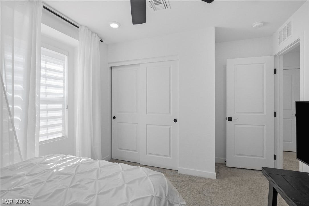 A well-lit sleeping area features neutral tones, soft carpeting, and a discreet closet.