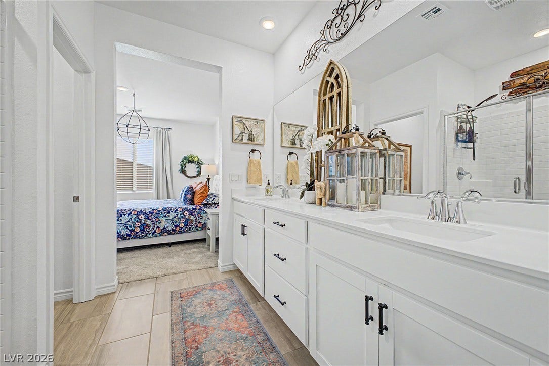 290 Fossil Falls Street, Henderson, NV 89015 Double vanities with sleek white countertops and ample storage complement the bright, inviting bedroom just beyond.