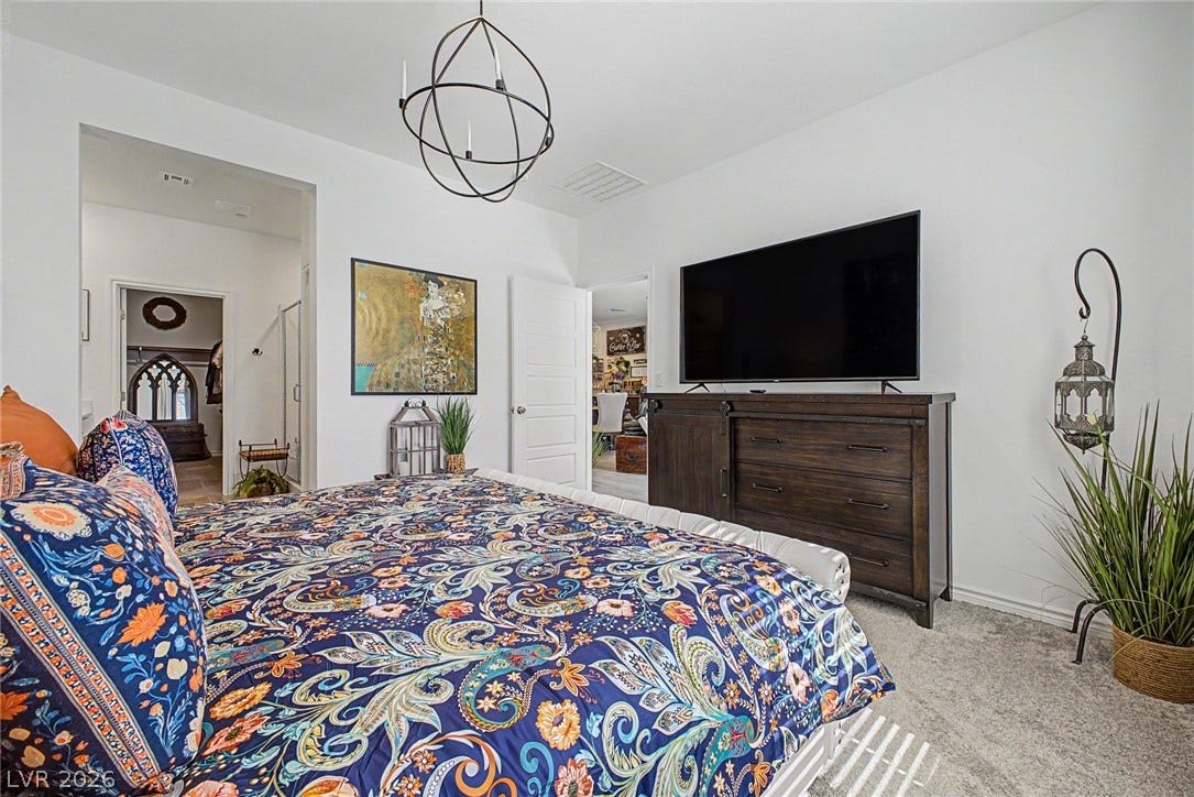 290 Fossil Falls Street, Henderson, NV 89015 A restful primary bedroom retreat features plush carpeting and an elegant orb chandelier.