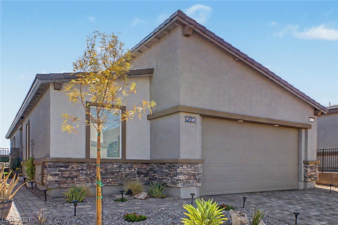 290 Fossil Falls Street, Henderson, NV 89015 A well-maintained stucco home with stone accents presents a welcoming curb appeal and an attached garage.