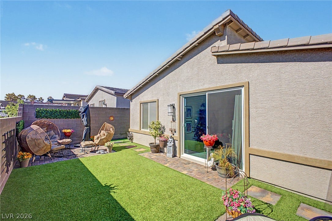 290 Fossil Falls Street, Henderson, NV 89015 A well-appointed outdoor patio features a blend of artificial turf and paver pathways, ideal for relaxation and entertaining.