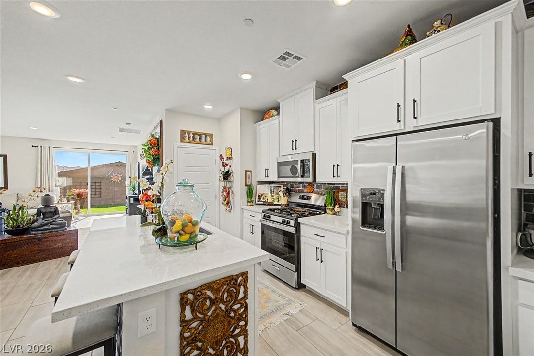 290 Fossil Falls Street, Henderson, NV 89015 A well-appointed kitchen features stainless steel appliances, a generous island with counter seating, and an open layout connecting to the living area.
