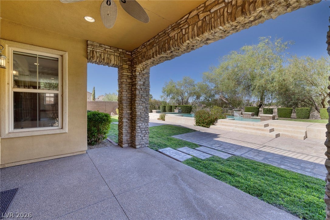30 Benevolo Drive, Henderson, NV 89011 An inviting covered patio featuring stone pillars overlooks a meticulously landscaped yard with a sparkling pool.