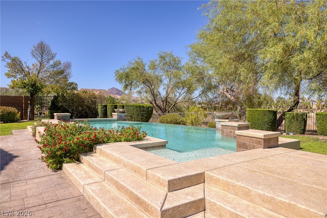 30 Benevolo Drive, Henderson, NV 89011 An inviting in-ground pool with integrated steps beckons, surrounded by manicured landscaping and mountain vistas.