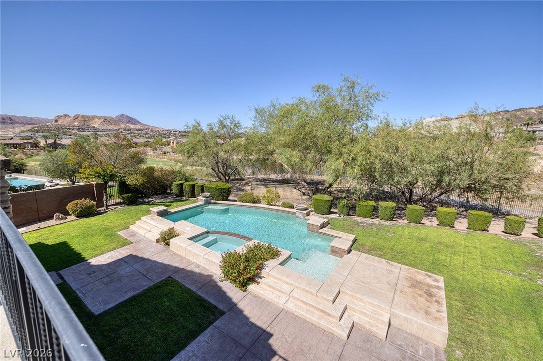 30 Benevolo Drive, Henderson, NV 89011 An inviting backyard oasis awaits with a sparkling pool and spa, set against a scenic mountain and golf course backdrop.