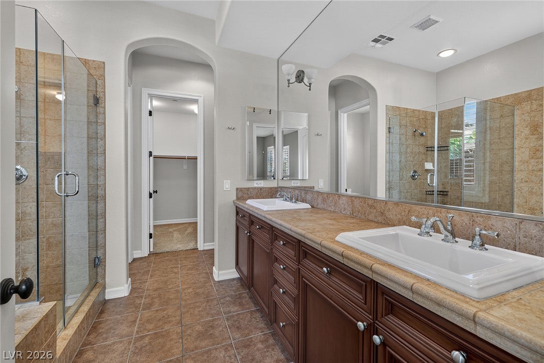 30 Benevolo Drive, Henderson, NV 89011 Double vanities and an oversized mirror amplify this bathroom's elegant appeal, complemented by a spacious glass-enclosed shower.