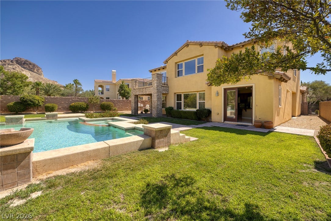 30 Benevolo Drive, Henderson, NV 89011 An inviting backyard oasis offers a sparkling pool and spa, set against a distant mountain backdrop.