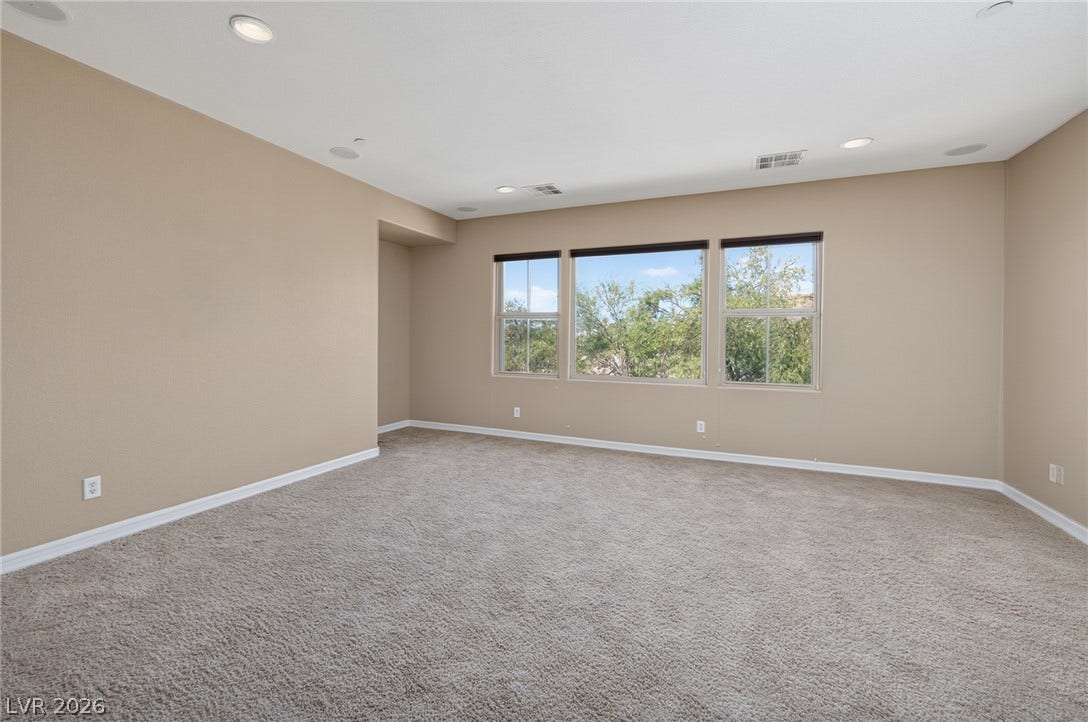30 Benevolo Drive, Henderson, NV 89011 A spacious room offers ample natural light and a serene tree-filled outlook through multiple windows.