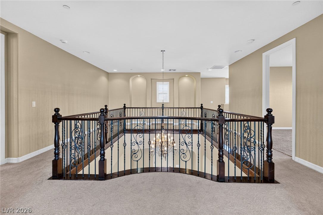 30 Benevolo Drive, Henderson, NV 89011 A graceful staircase with intricate ironwork leads to the upper level's open landing, illuminated by a sparkling chandelier.