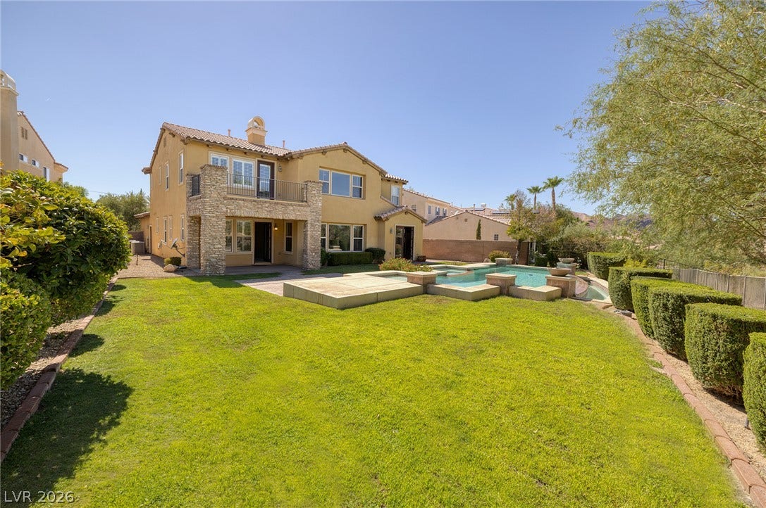 30 Benevolo Drive, Henderson, NV 89011 A well-maintained lawn stretches towards a home featuring a second-story balcony and an inviting swimming pool.