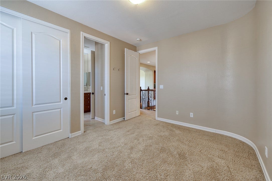 30 Benevolo Drive, Henderson, NV 89011 A well-lit bedroom features plush carpeting and convenient access to a private bathroom and hallway.