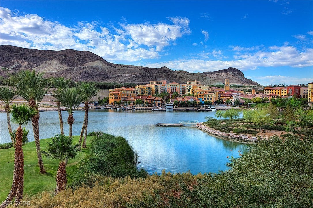 30 Benevolo Drive, Henderson, NV 89011 A tranquil lake view unfolds before a vibrant community nestled against a majestic mountain range.