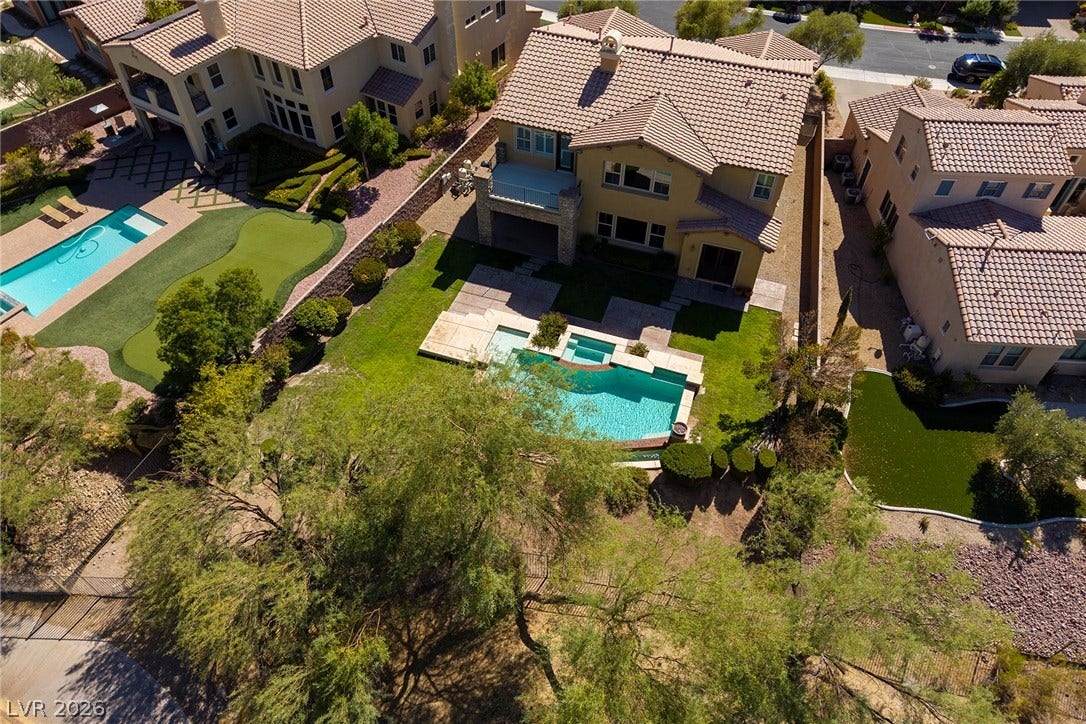 30 Benevolo Drive, Henderson, NV 89011 An aerial perspective showcases a lavish backyard retreat, complete with a sparkling pool, manicured lawn, and dedicated putting green.