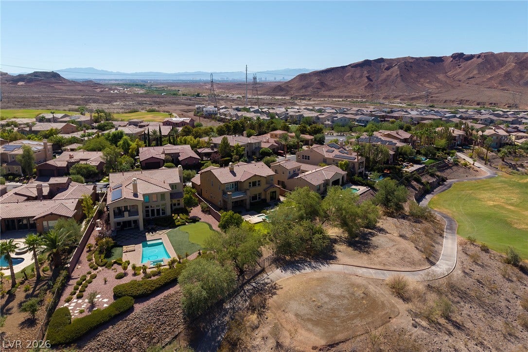 30 Benevolo Drive, Henderson, NV 89011 An aerial perspective reveals a vibrant neighborhood amidst a desert landscape, boasting private pools and direct golf course access.