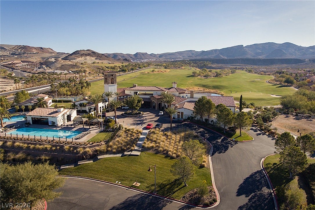 30 Benevolo Drive, Henderson, NV 89011 An aerial perspective reveals a sprawling resort-style community with a golf course and swimming pool nestled among rolling hills.