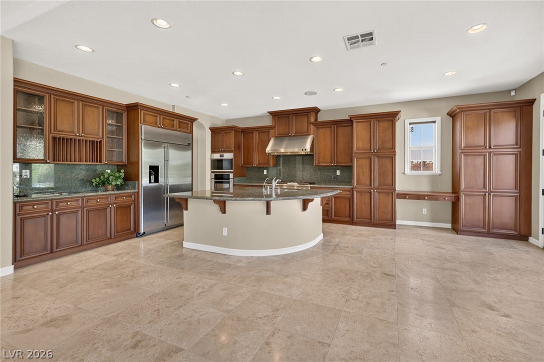 30 Benevolo Drive, Henderson, NV 89011 An inviting kitchen features a large curved island, abundant cabinetry, and integrated appliances.