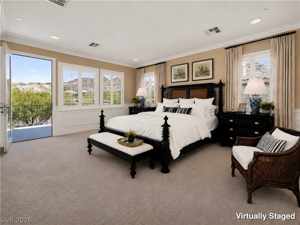 30 Benevolo Drive, Henderson, NV 89011 An inviting bedroom with plush carpeting, offering tranquil views of the mountains and neighborhood through an open door and ample windows.