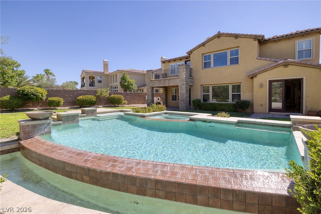 30 Benevolo Drive, Henderson, NV 89011 An inviting backyard oasis offers a sparkling pool with an integrated spa, set against a beautifully designed home exterior.