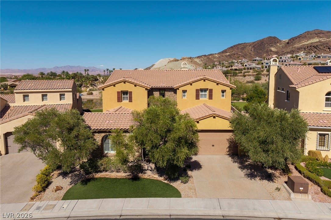 30 Benevolo Drive, Henderson, NV 89011 A desert oasis, this two-story residence presents a warm stucco facade against a backdrop of rugged mountains.