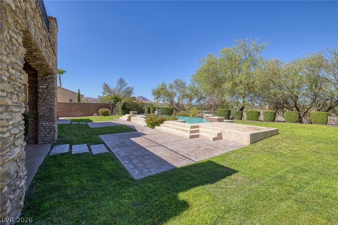 30 Benevolo Drive, Henderson, NV 89011 A lavish backyard oasis with a serene pool and stone patio, perfect for luxurious outdoor living.