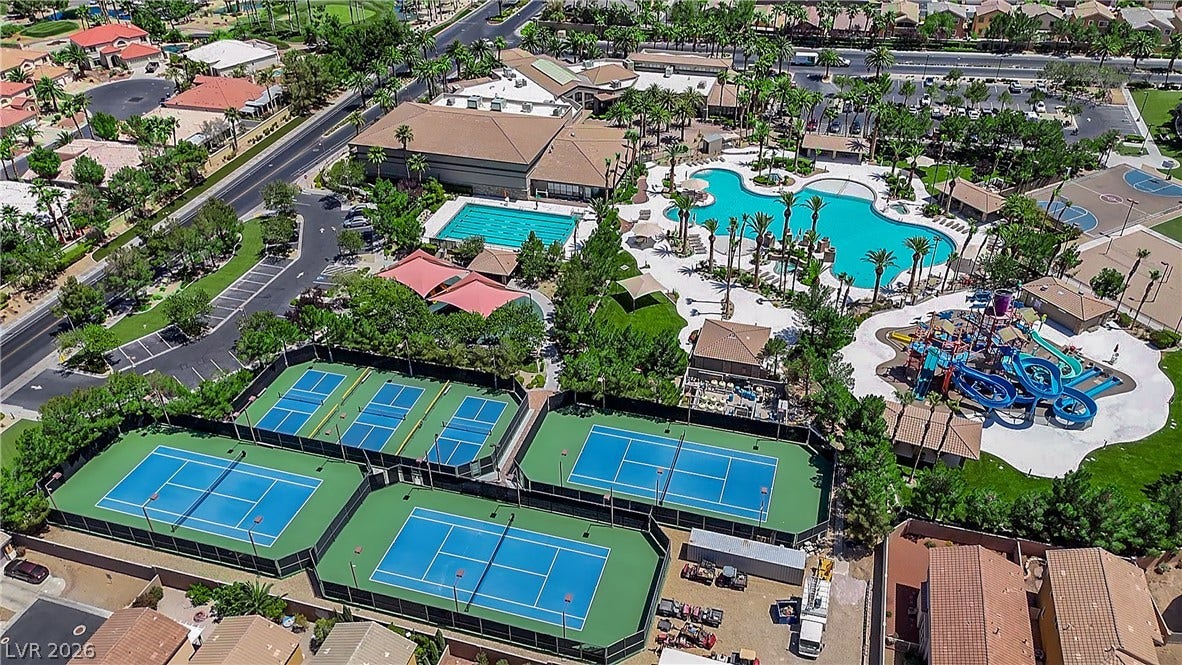 771 White Dogwood Court, Las Vegas, NV 89148 An aerial view captures the vibrant community amenities, showcasing multiple pools, waterslides, and tennis courts.