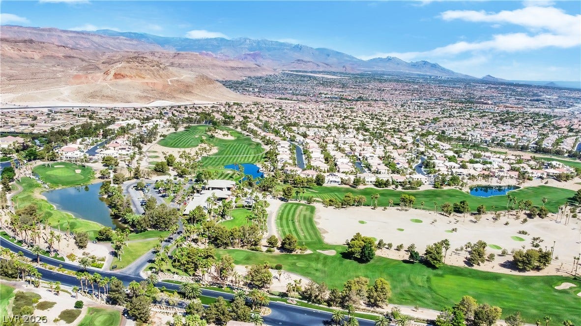 771 White Dogwood Court, Las Vegas, NV 89148 An aerial perspective reveals a vibrant golf course community nestled against a striking mountain backdrop.