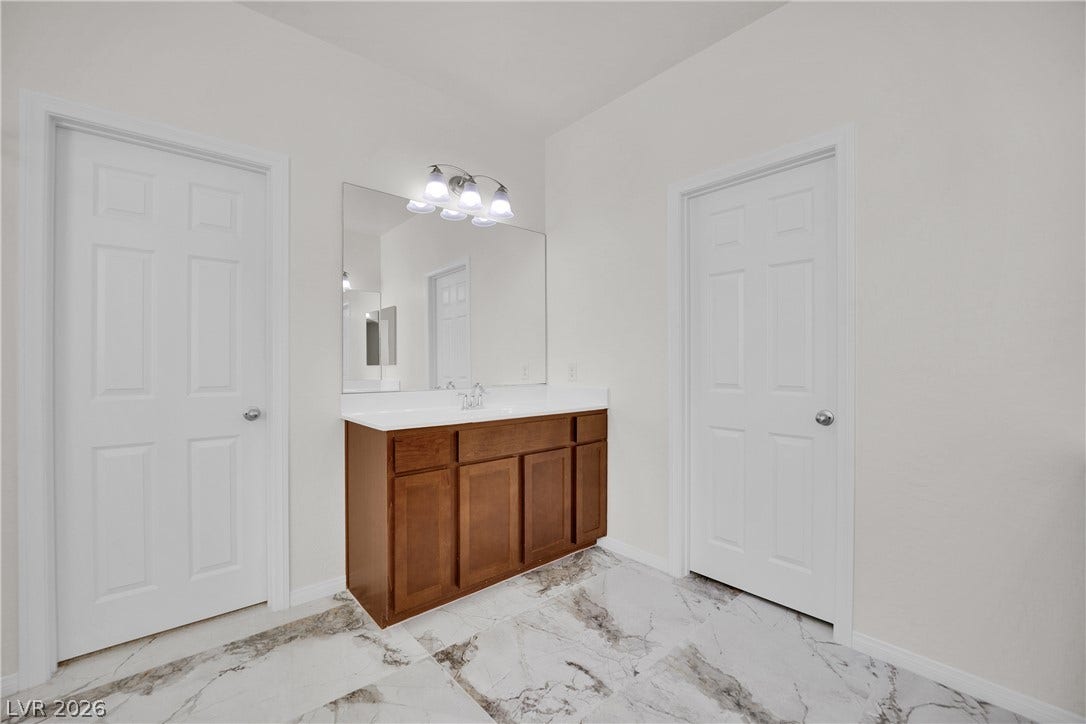 771 White Dogwood Court, Las Vegas, NV 89148 A well-appointed bathroom features a single vanity with ample storage, complemented by a large mirror and bright overhead lighting.
