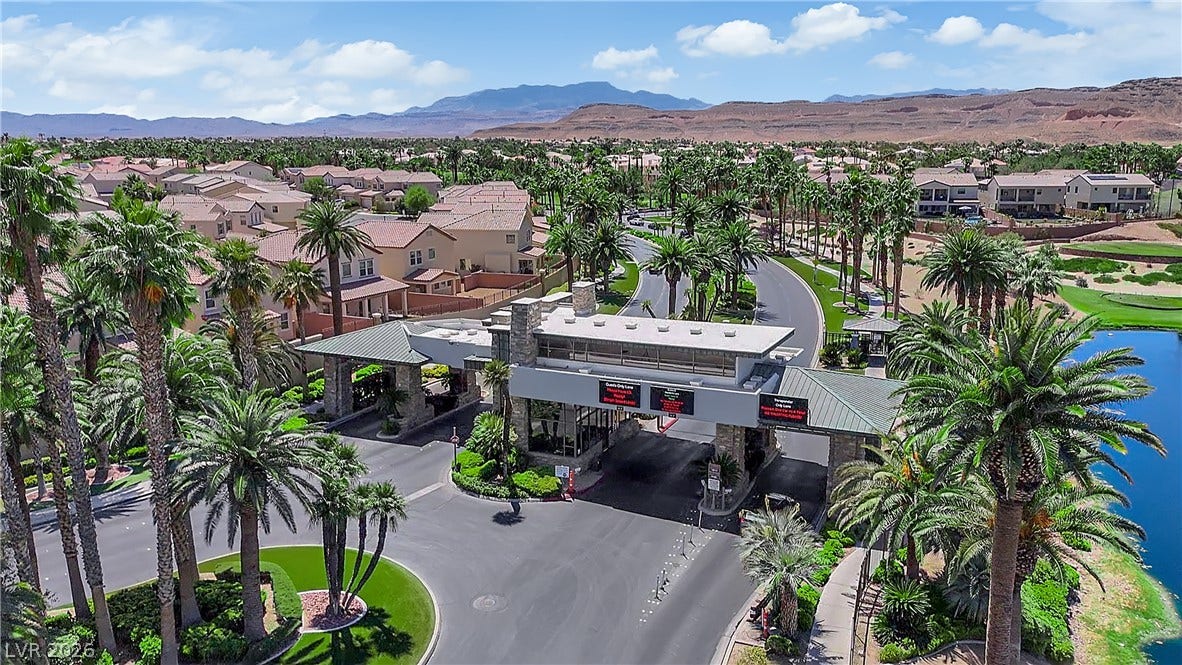771 White Dogwood Court, Las Vegas, NV 89148 Gated entry into a residential community featuring abundant palm trees, lush golf course, and distant mountains.