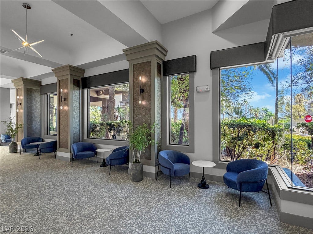 771 White Dogwood Court, Las Vegas, NV 89148 A refined lounge area with sleek seating and expansive windows offers views of lush outdoor landscaping.