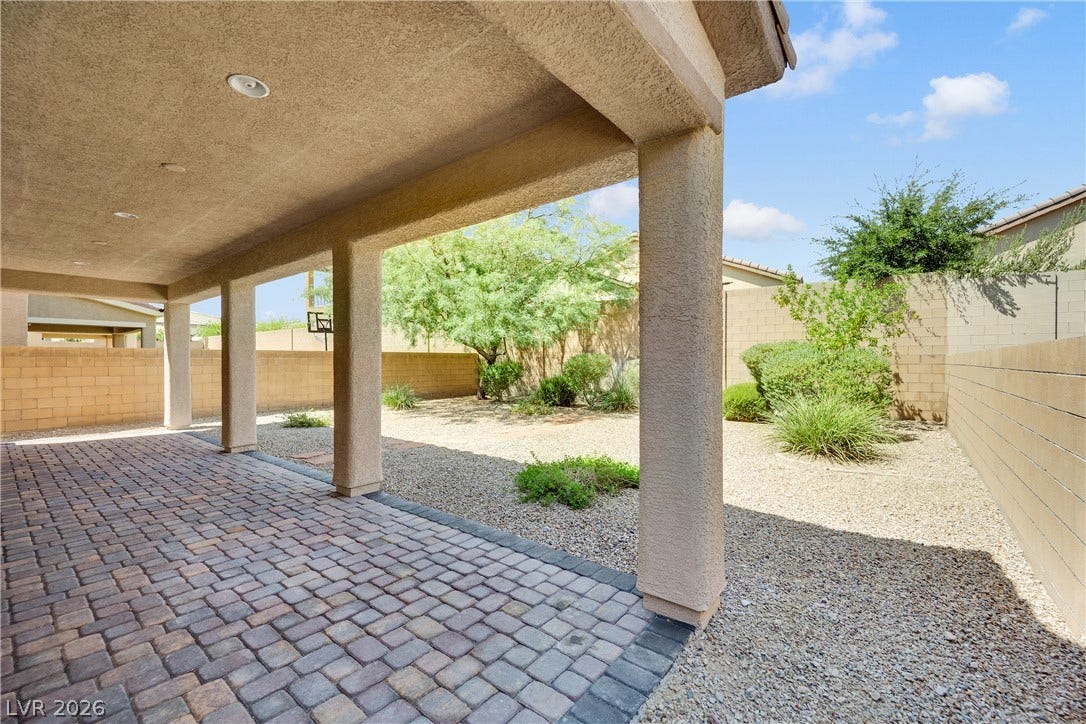 771 White Dogwood Court, Las Vegas, NV 89148 An inviting covered patio featuring paver flooring extends into a xeriscaped backyard enclosed by block fencing.