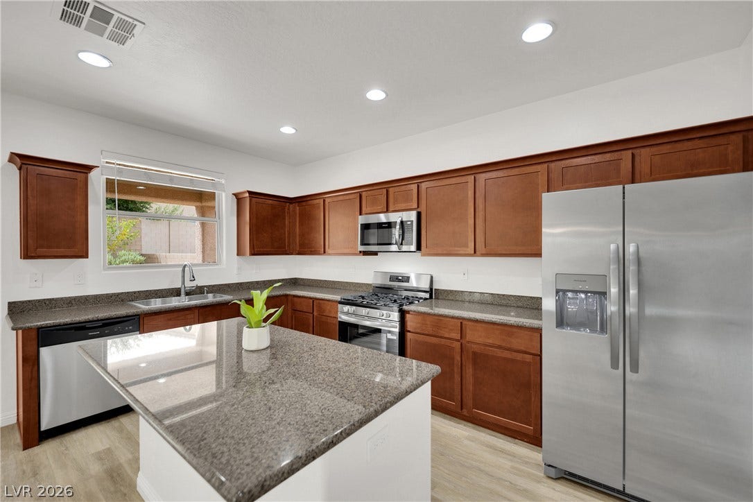 771 White Dogwood Court, Las Vegas, NV 89148 Polished stone countertops and rich wood cabinetry anchor this modern culinary space.