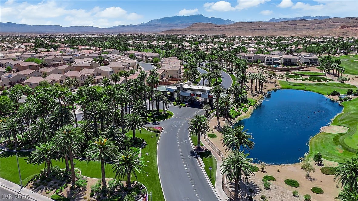 771 White Dogwood Court, Las Vegas, NV 89148 An aerial perspective reveals a gated community nestled beside a golf course, with desert mountains providing a dramatic backdrop.