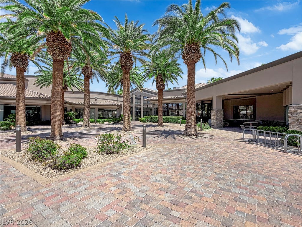 771 White Dogwood Court, Las Vegas, NV 89148 Mature palm trees adorn the paver stone courtyard, leading to a welcoming building entrance.