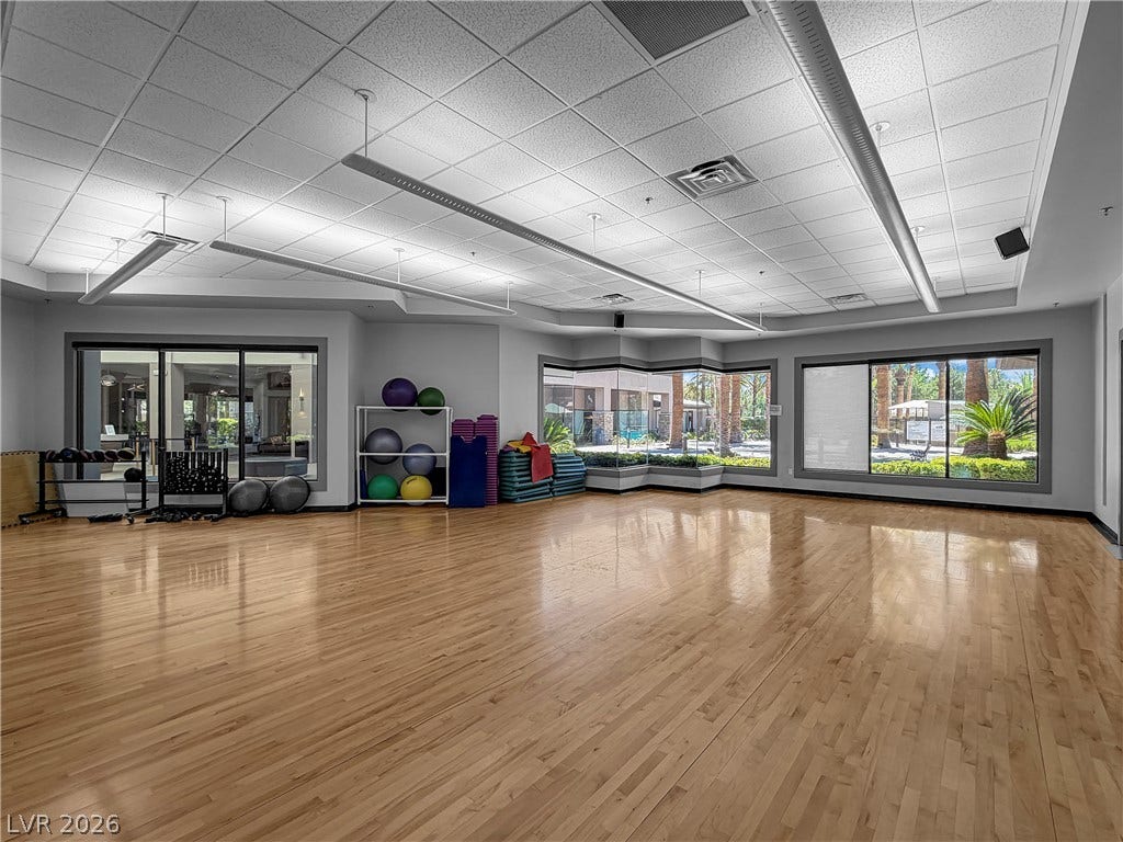 771 White Dogwood Court, Las Vegas, NV 89148 A spacious fitness room with gleaming hardwood floors invites an active lifestyle, featuring generous windows overlooking lush greenery.