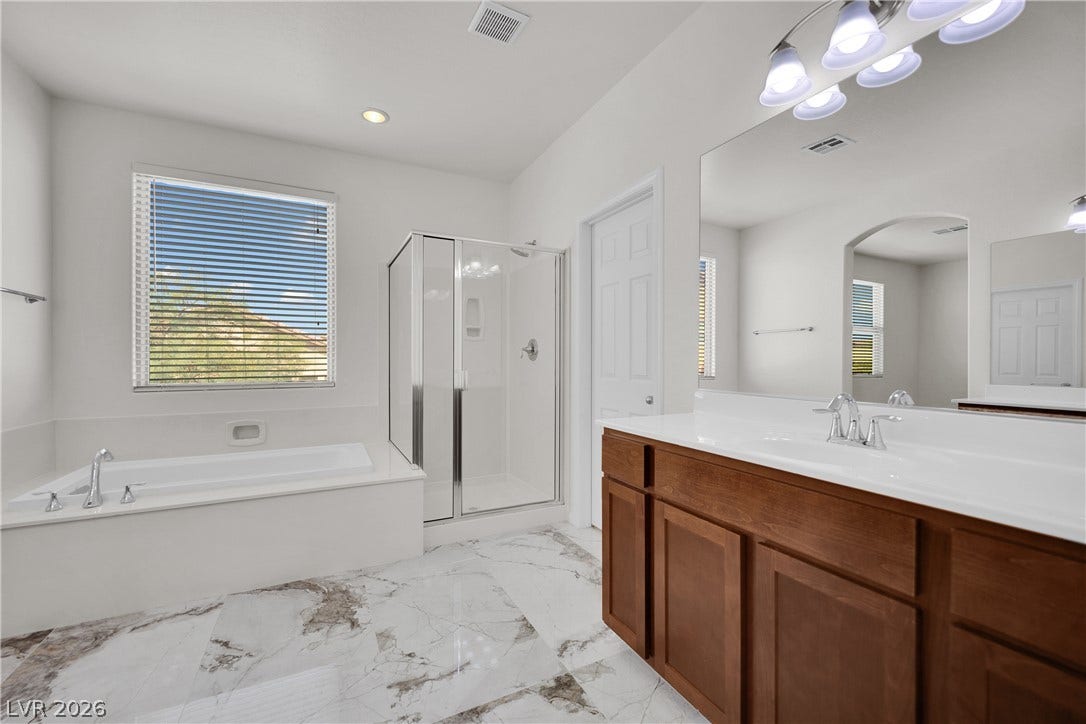 771 White Dogwood Court, Las Vegas, NV 89148 A well-lit primary bathroom featuring a spacious walk-in shower and a deep soaking tub, perfect for unwinding.