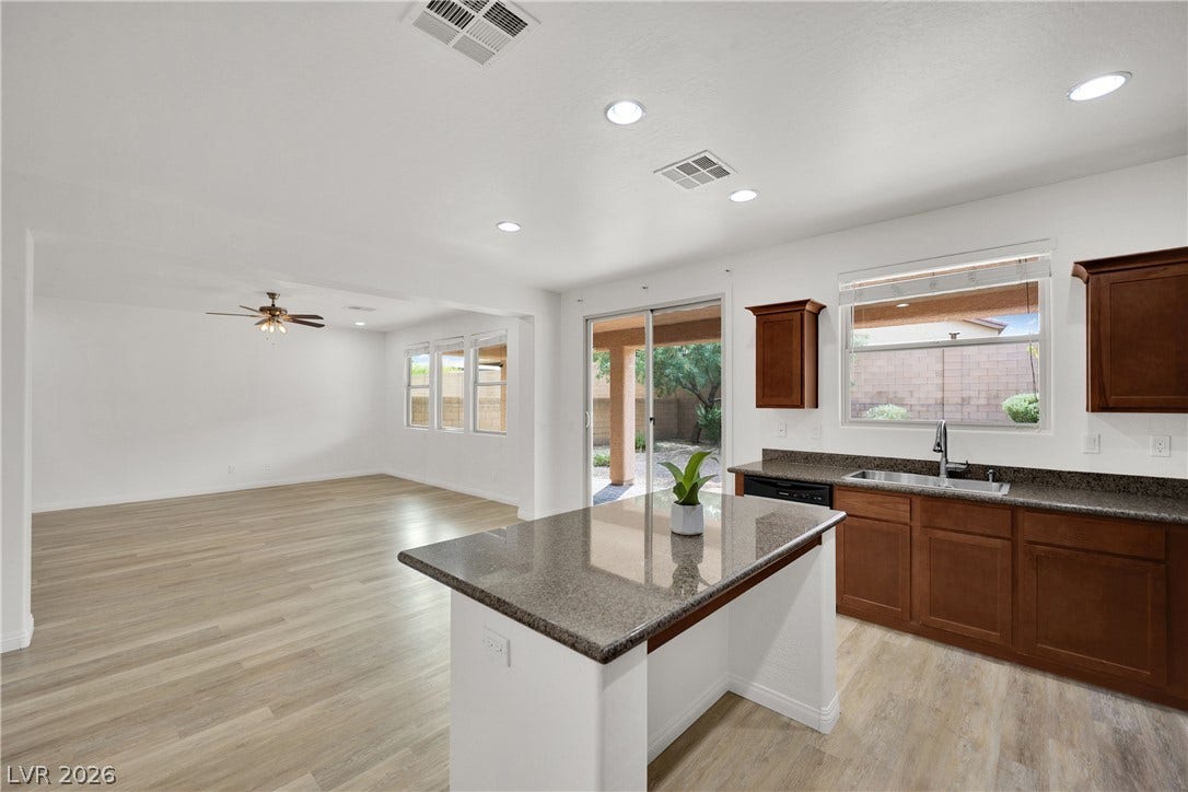 771 White Dogwood Court, Las Vegas, NV 89148 Polished granite countertops and light wood-look flooring anchor this airy open kitchen design.