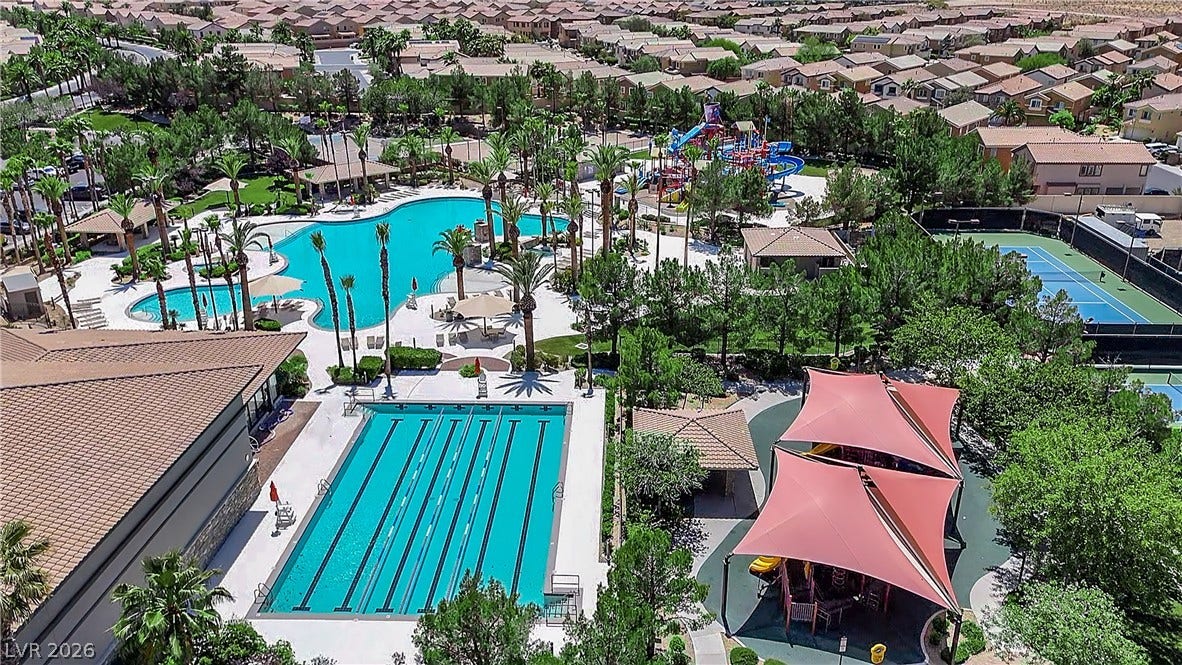 771 White Dogwood Court, Las Vegas, NV 89148 An aerial perspective reveals a vibrant community with pools, recreation facilities, and lush landscaping, nestled among residential rooftops.