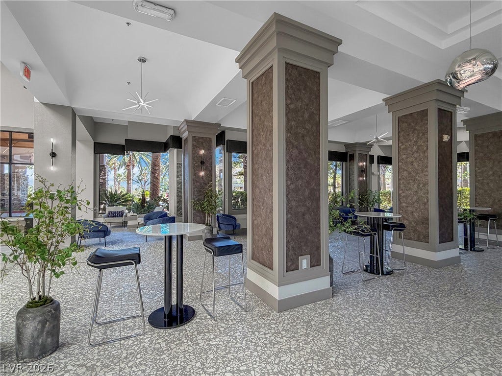 771 White Dogwood Court, Las Vegas, NV 89148 A spacious common area with soaring ceilings and large windows, offering a view of lush palm trees.