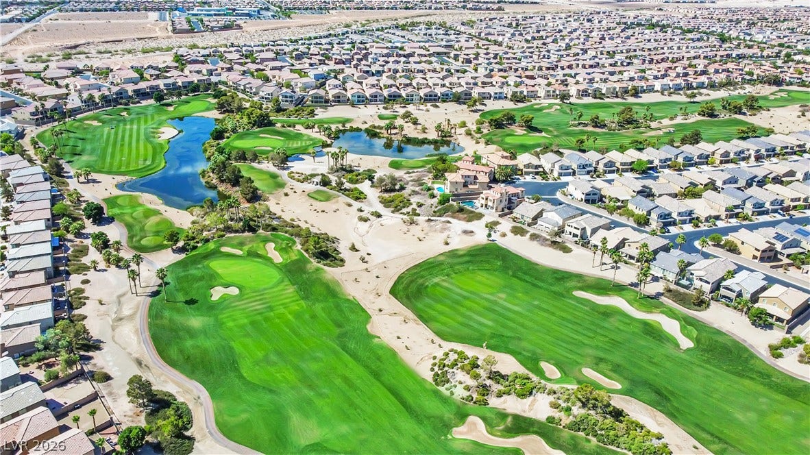 771 White Dogwood Court, Las Vegas, NV 89148 An aerial perspective reveals a vast community nestled around a meticulously manicured golf course with shimmering water features.