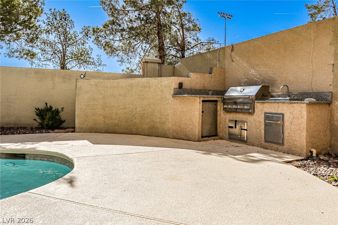 1828 Dolce Drive, Las Vegas, NV 89134 An inviting outdoor kitchen area with built-in grill and sink provides perfect al fresco dining by the pool.