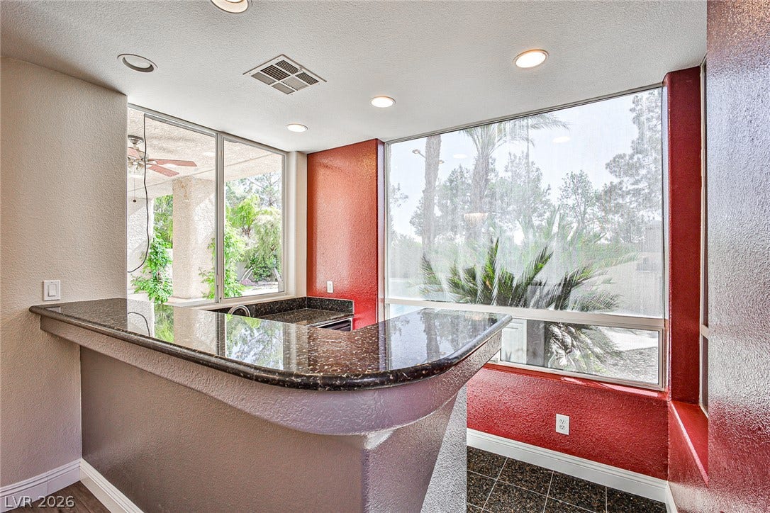 1828 Dolce Drive, Las Vegas, NV 89134 A well-appointed wet bar area, complete with sleek countertops and expansive windows overlooking the exterior patio.