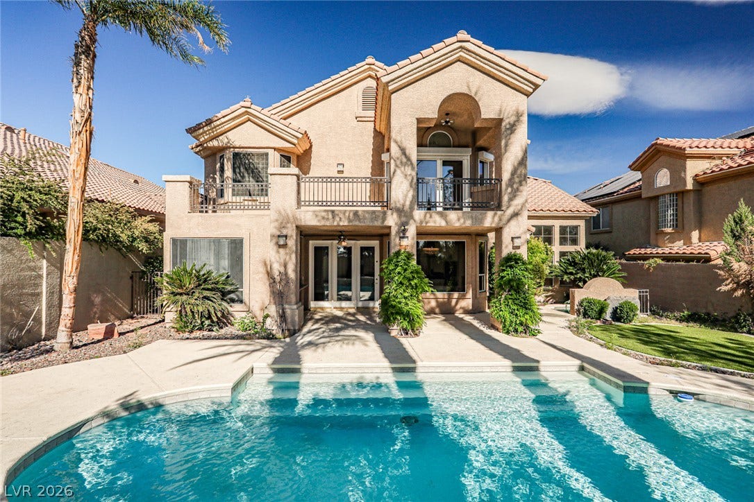 1828 Dolce Drive, Las Vegas, NV 89134 An inviting backyard oasis offers a sparkling pool and a grand two-story home with multiple balconies.