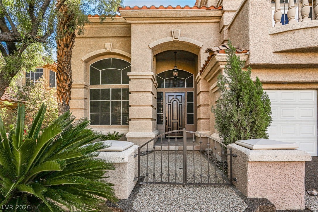 1828 Dolce Drive, Las Vegas, NV 89134 A grand arched entry welcomes guests to this Mediterranean-inspired residence, boasting decorative windows and a private gate.