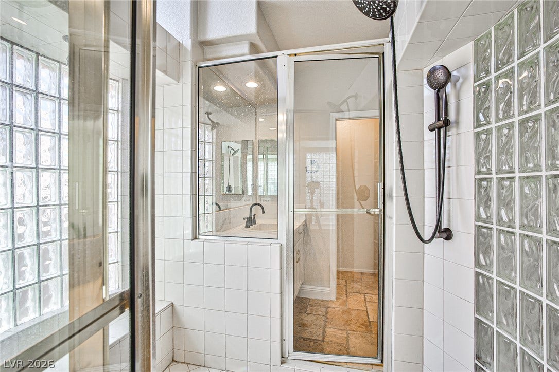 1828 Dolce Drive, Las Vegas, NV 89134 A well-appointed shower space showcases glass block windows and a rain showerhead for a refreshing experience.